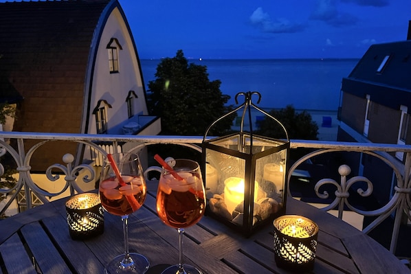 A balcony with two glasses of red wine, a candle, and a lantern. - 3-room apartment in Sandwall, approx. 55 m², with a view of the sea (Wyk auf Föhr)