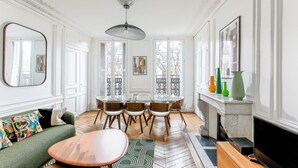 A dining area with a round table, chairs, and a fireplace. - Appartements 4 boulevard Beaumarchais (Paris)