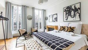 A modern bedroom with a large bed, a fireplace, and artwork on the walls. - Appartements 4 boulevard Beaumarchais (Paris)