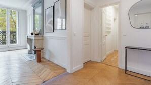 A spacious room with a herringbone floor pattern, a fireplace, and a large mirror on the wall. - Appartements 4 boulevard Beaumarchais (Paris)