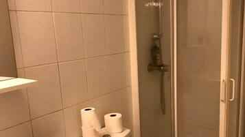 Een douche, handdoeken, zeep, toiletpapier