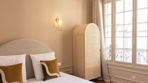 Un grand lit avec une tête de lit, une lampe de chevet et une fenêtre donnant sur l’extérieur.