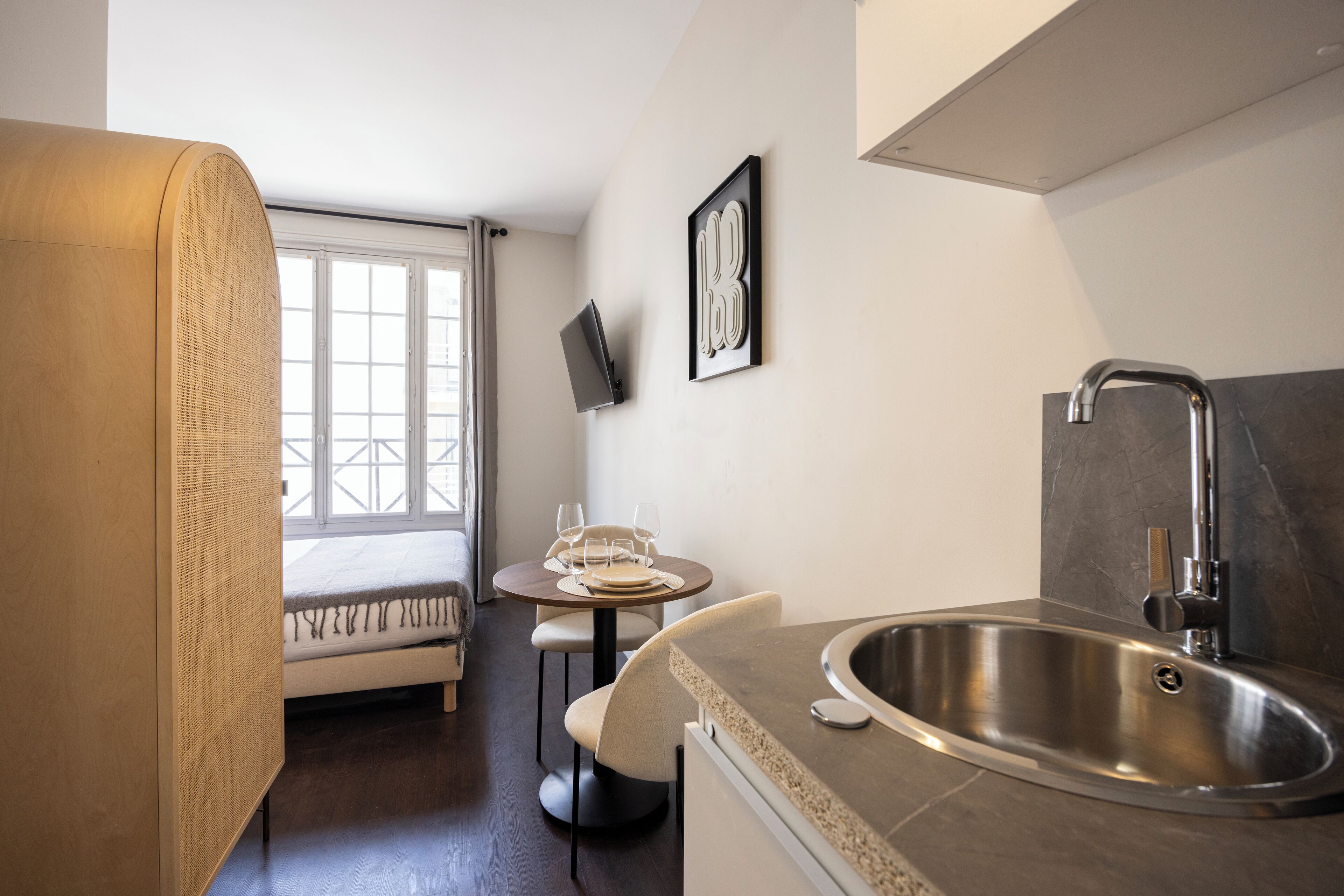 A compact kitchen with a sink, a dining area with a table and chairs, and a window with a view.