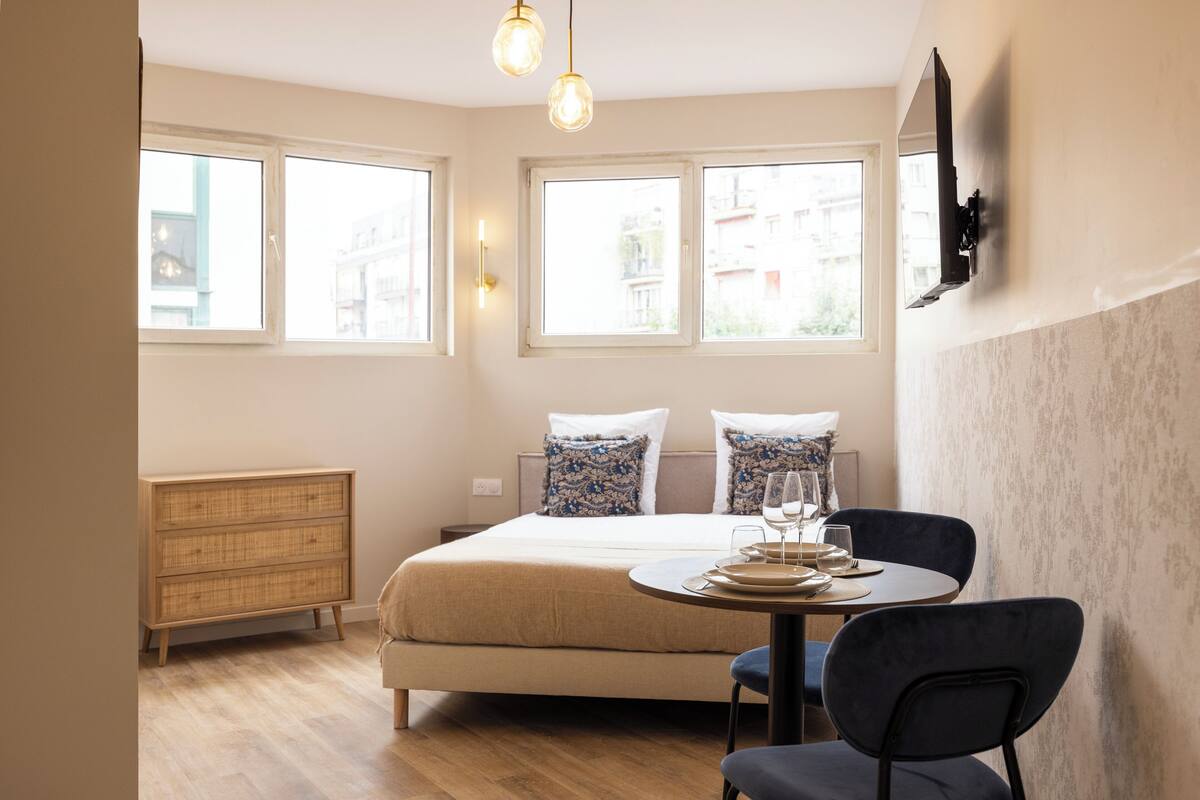 Una camera da letto con un letto, un comodino e un'area pranzo con tavolo e sedie.