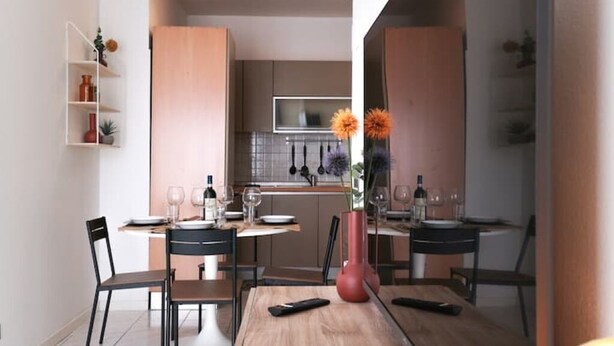 A modern dining area with a wooden table, black chairs, and a vase with flowers.