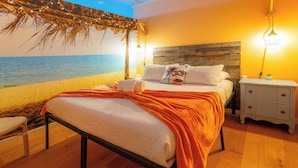 A bedroom with a bed, nightstands, a small table, and a beach mural on the wall. - Jungle Haven, Heated Pool, Fun for 12 (Johnson City)