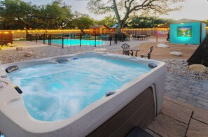 A hot tub with a pool in the background, surrounded by a fenced area with string lights. - Jungle Haven, Heated Pool, Fun for 12 (Johnson City)