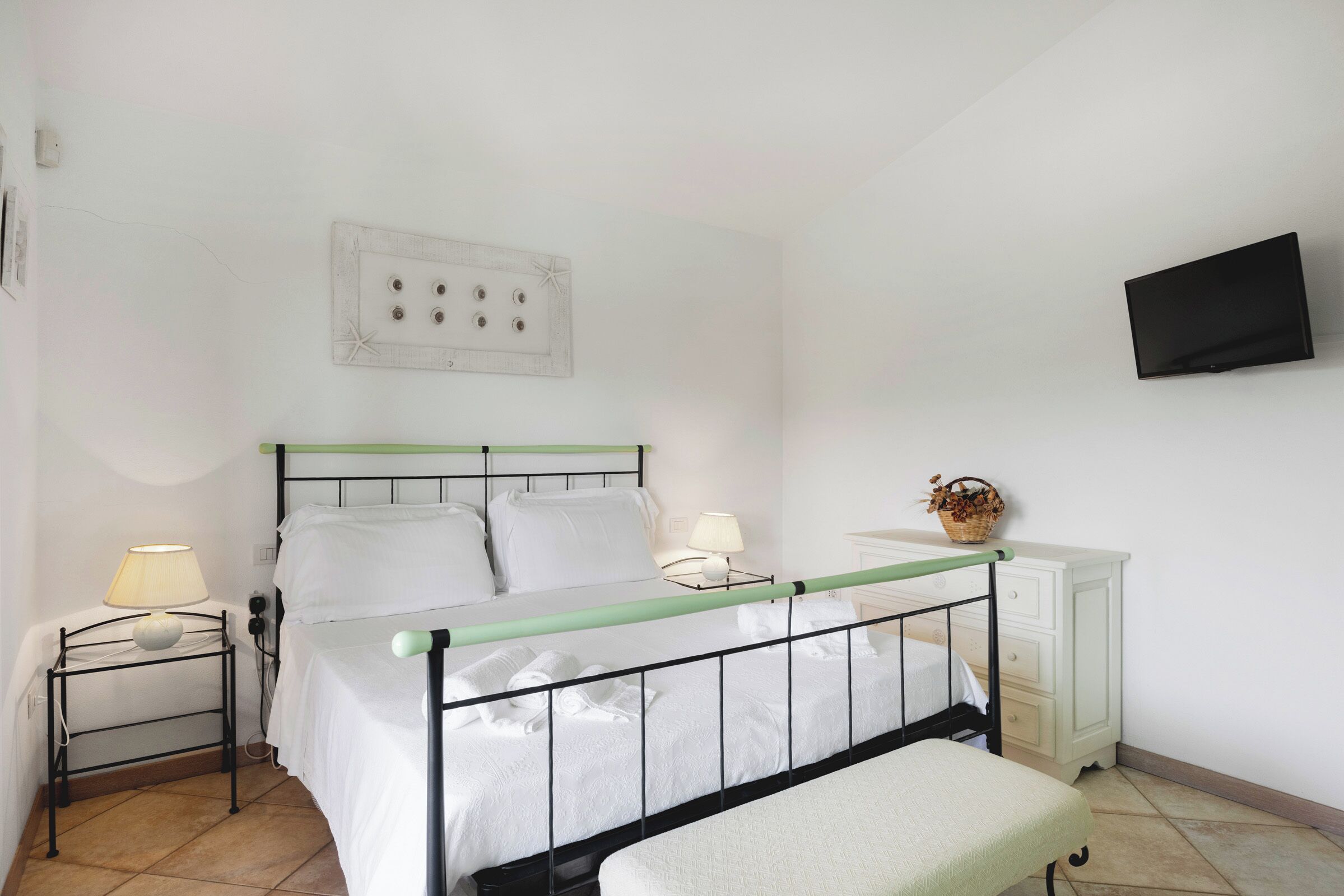 Ein Schlafzimmer mit einem Bett, Nachttischen, einem Fernseher und einer Kommode.