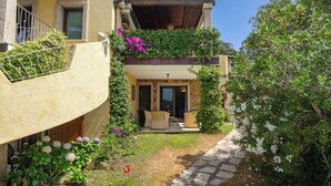 Une maison à deux étages avec un balcon, un chemin de pierre et un jardin fleuri.