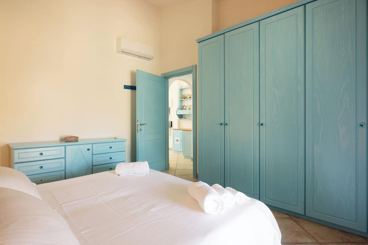 A bedroom with a bed, a dresser, and a wardrobe.