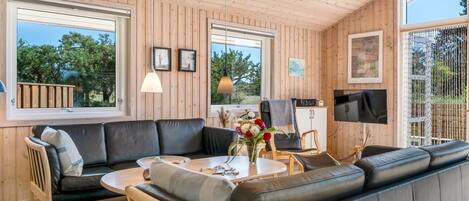 Una sala de estar moderna con un sofá de cuero negro, una mesa de centro redonda y un televisor montado en la pared.