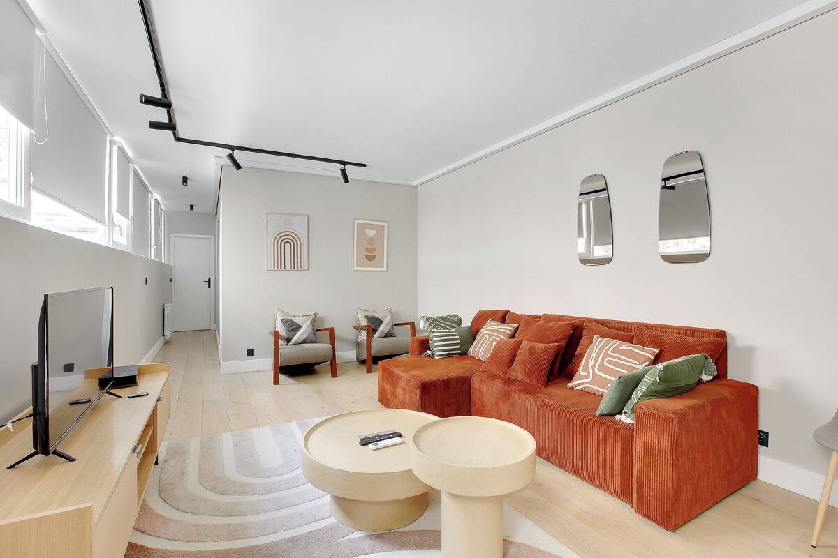 A modern living room with a sectional sofa, a coffee table, and a TV on a stand.