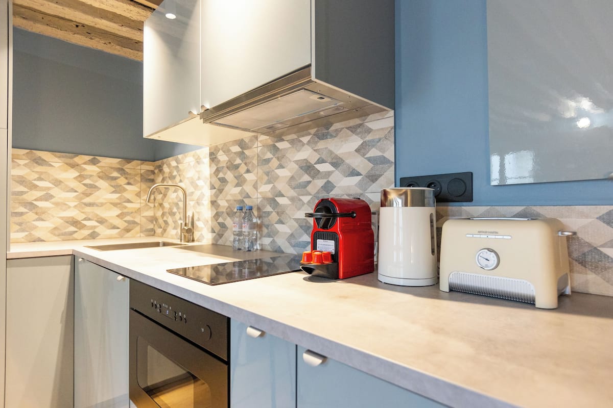 A modern kitchen with a dishwasher, a coffee maker, and a toaster on the counter.