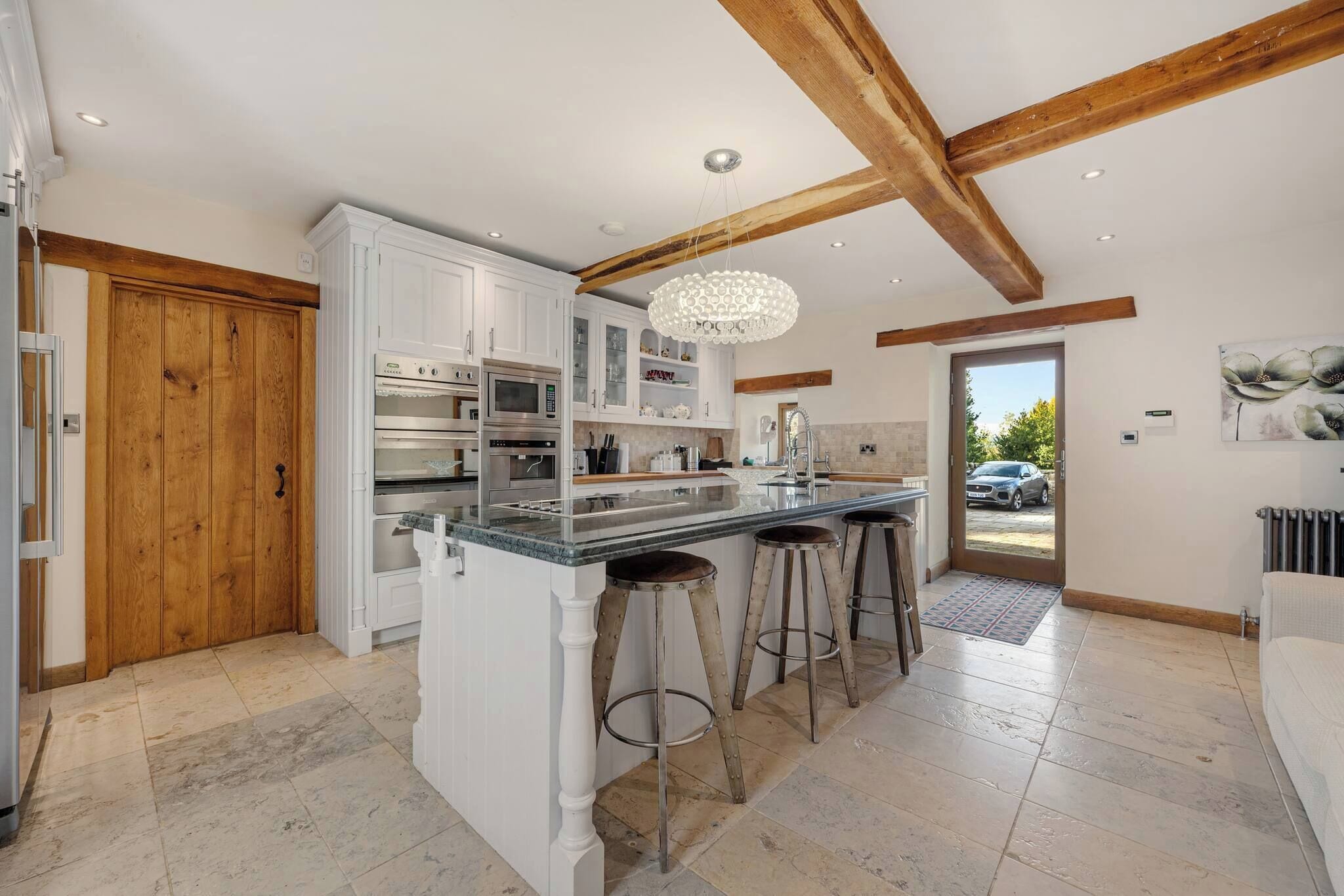 Una cocina moderna con armarios blancos, una isla central con taburetes y techo de madera.