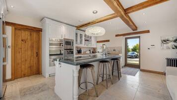 Una cocina moderna con armarios blancos, una isla central con taburetes y techo de madera.