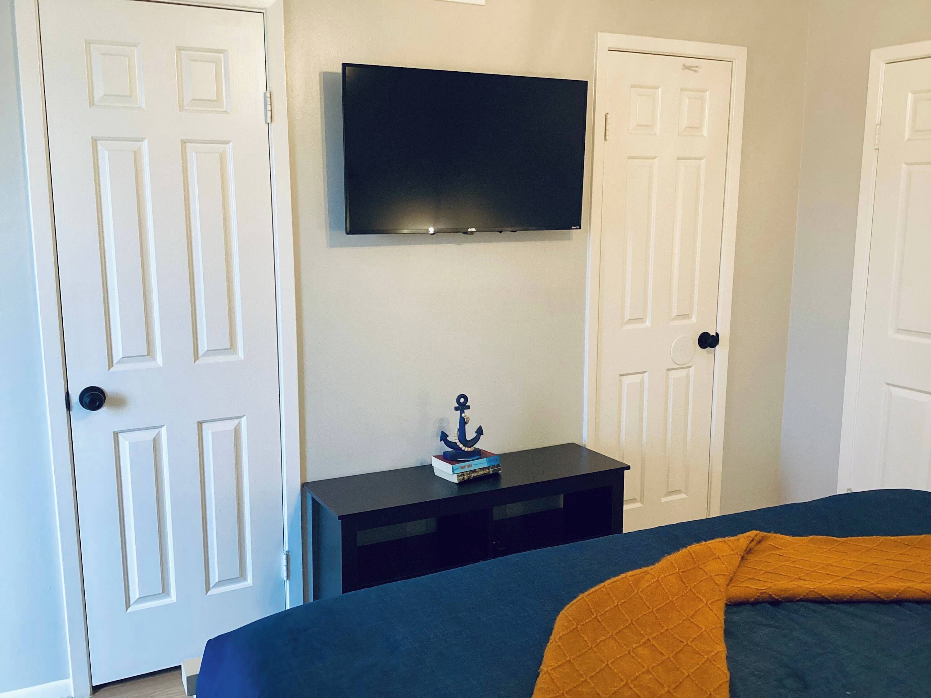 Una camera da letto con un letto, una TV a parete e un tavolino con un oggetto decorativo.