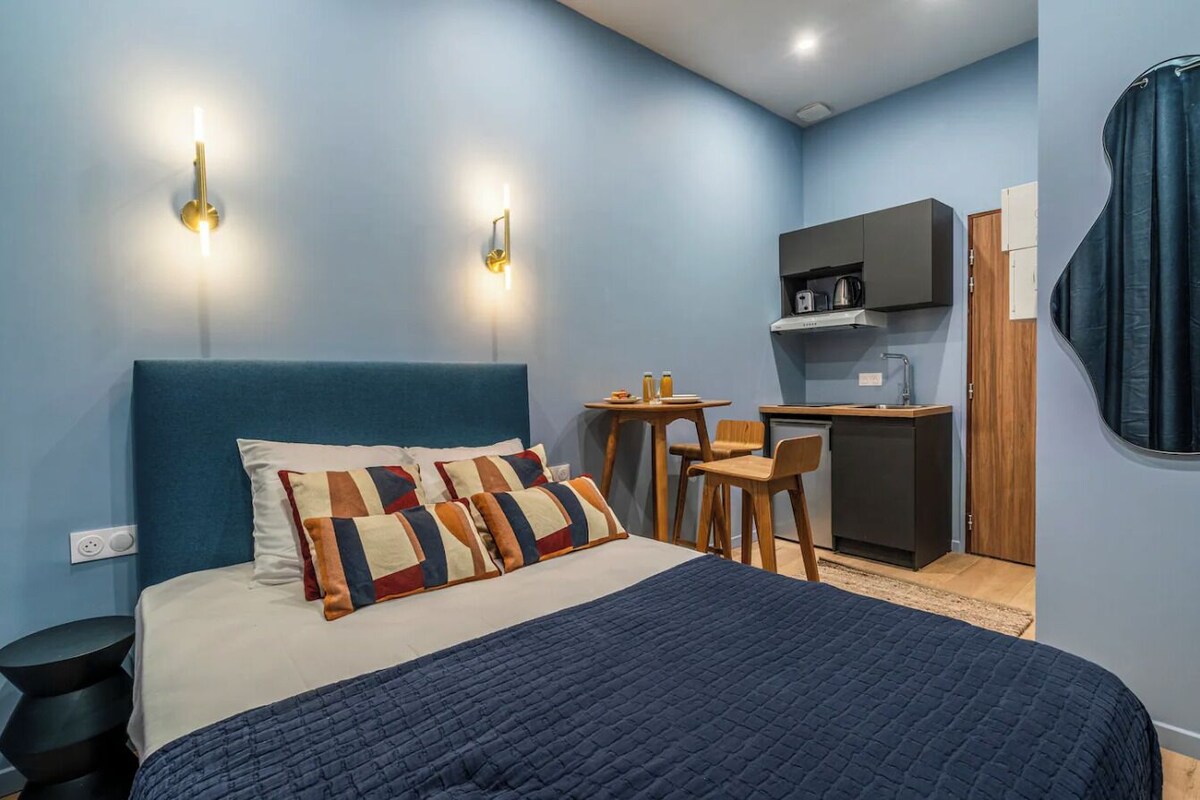 Un dormitorio con cama, escritorio y kitchenette.