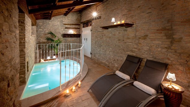 A spa area with a pool, two lounge chairs, and a small table with a lamp. - Villa ai Caprioli Mondaino (Emilia-Romagna)