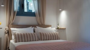 A neatly made bed with a pink quilt, white pillows, and striped pillows.