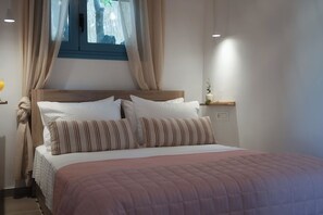 A neatly made bed with a pink quilt, white pillows, and striped pillows.