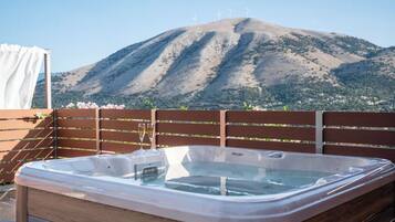 Un jacuzzi con cubierta de madera y vista a las montañas al fondo.