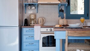 A kitchen with blue cabinets, a white refrigerator, a stove, and a window with a view of the outside.