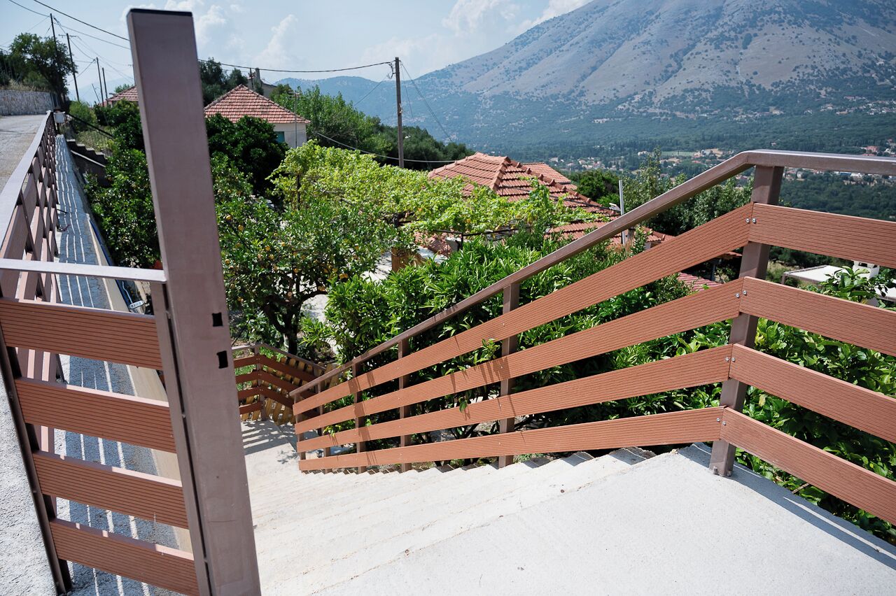 Una escalera con barandillas de madera que lleva a una zona residencial con casas y una montaña al fondo.