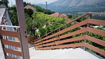 Una escalera con barandillas de madera que lleva a una zona residencial con casas y una montaña al fondo.
