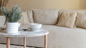 A beige sofa with a textured throw pillow and a white bowl on a marble table. - Le Cocon 🦋 Apartment in the heart of Thonon les bains ! (Thonon-les-Bains)