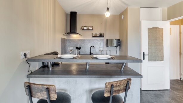 A modern kitchen with a central island, two bar stools, a built-in oven, and a pendant light. - Le Cocon 🦋 Apartment in the heart of Thonon les bains ! (Thonon-les-Bains)