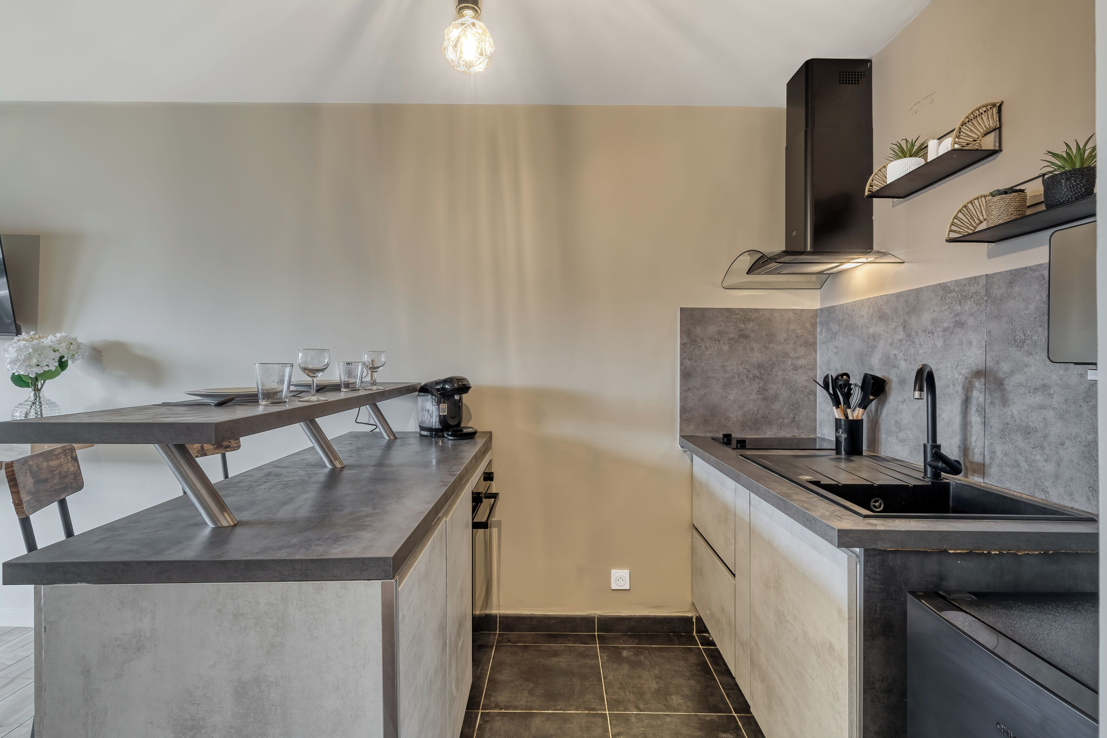 A modern kitchen with a central island, built-in oven, and a stainless steel sink.