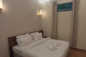 Ein Hotelzimmer mit Bett, einem Fenster mit Vorhängen und einer Wandleuchte.