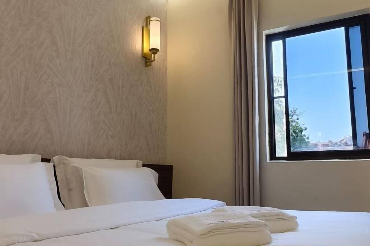 Ein Hotelzimmer mit einem Bett, einer Wandleuchte und einem Fenster mit Vorhängen.
