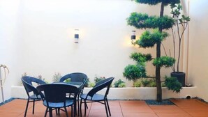 An outdoor patio with a table and chairs, surrounded by potted plants and a small tree. - Guan Gong Hotel Jin Shang Development Jonker Street (Melaka)