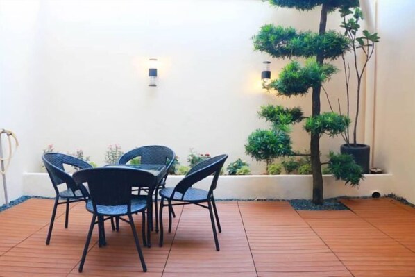 An outdoor patio with a table and chairs, surrounded by potted plants and a small tree. - Guan Gong Hotel Jin Shang Development Jonker Street (Melaka)