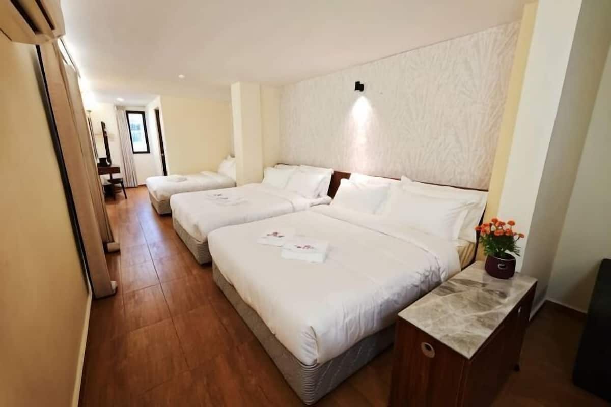 Ein Hotelzimmer mit zwei Betten, Holzboden, Nachttisch aus Marmor und einer kleinen Pflanze.