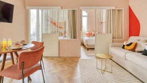 A hotel room with a dining area, a sofa, and a TV. - Appartements avenue Gourgaud (Paris)