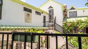 A building with a sign indicating it is a heritage hotel, a staircase, and a balcony with plants. - Baz-Art Eco Guest House (Rodrigues Island)