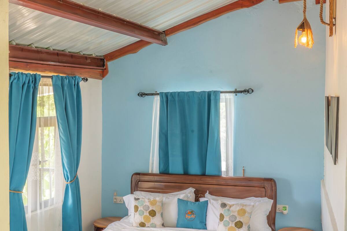 Un dormitorio con una cama de madera, un ventilador de techo y una ventana con cortinas.