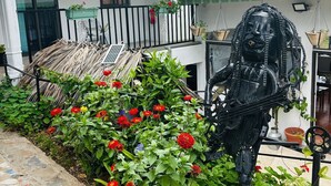 A courtyard with a metal sculpture, potted plants, and a tiled pathway. - Baz-Art Eco Guest House (Rodrigues Island)