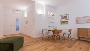 A modern living room with a wooden dining table, four chairs, a green ottoman, and a wooden cabinet. - Ormea Cobalto Apartment by Wonderful Italy (Turin)