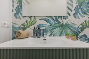 A bathroom with a white sink, two hair and body wash bottles, a towel, and two small potted plants. - Ormea Cobalto Apartment by Wonderful Italy (Turin)