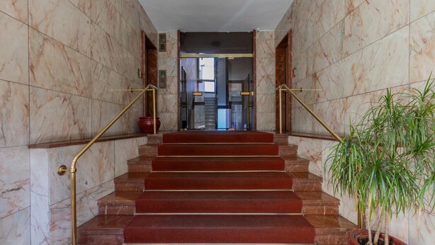 A marble staircase with red carpeted steps and brass railings, leading to a glass door entrance. - Ormea Cobalto Apartment by Wonderful Italy (Turin)