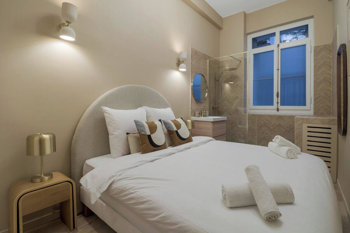 A modern hotel room with a large bed, bedside table, and a window with a view.