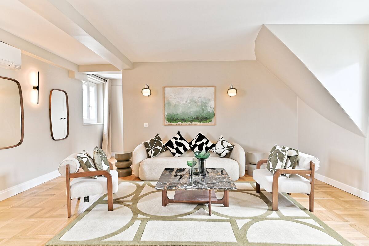 A modern living room with a sofa, two armchairs, a coffee table, and a painting on the wall.