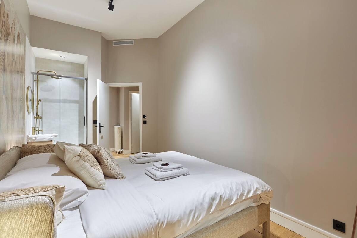 A spacious bedroom with a large bed, a walk-in closet, and a glass shower enclosure.