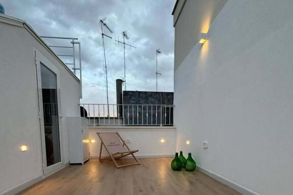 Una terraza en la azotea con piso de madera, una silla plegable y una mesita.