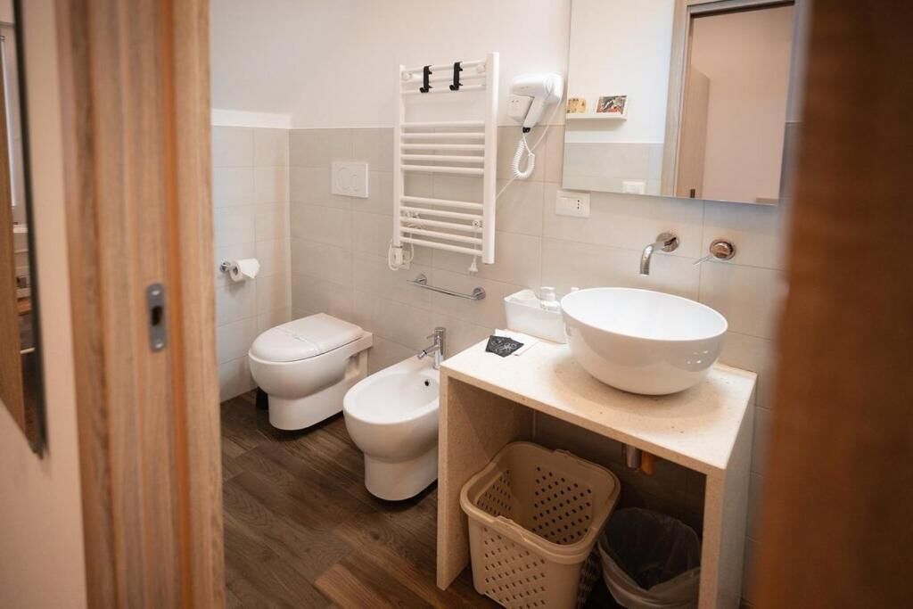 Une petite salle de bain comprenant des toilettes, un bidet et un lavabo doté d’un grand bac.