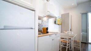 Una cocina moderna con armarios blancos, encimera de madera y comedor con sillas blancas.
