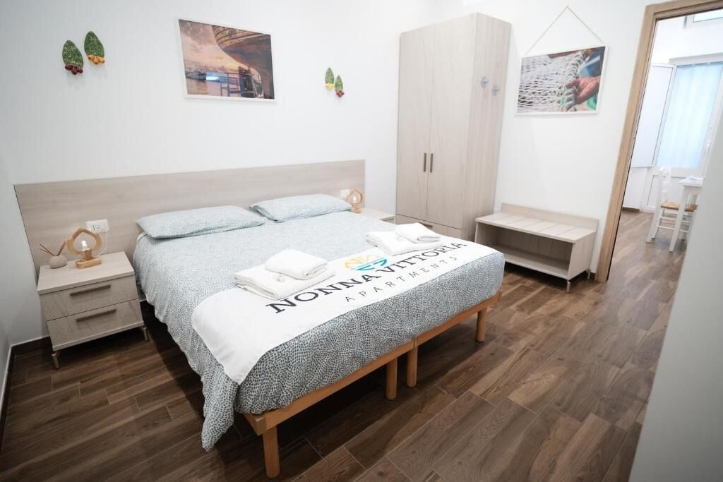 Un dormitorio con cama, mesitas de noche, armario y una banca.